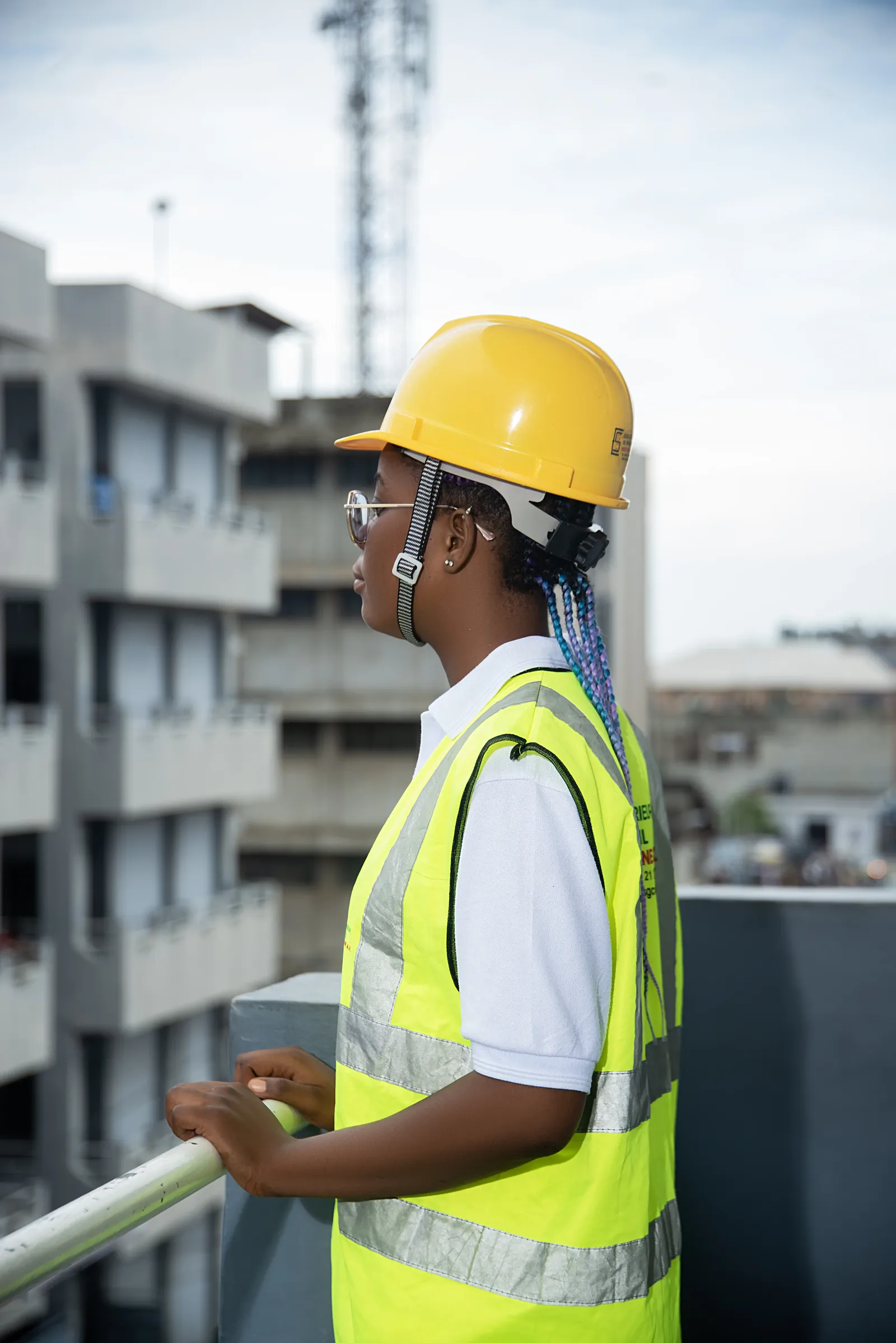 Étudiante en casque jaune et gilet de sécurité observant un chantier
